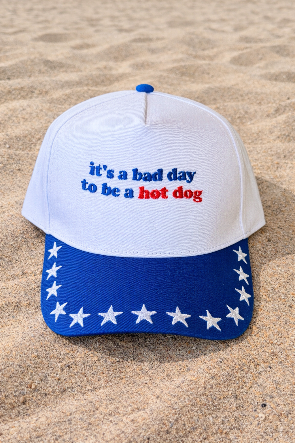 Blue "It’s A Bad Day To Be A Hot Dog" novelty hat from P&PD Wholesale, featuring playful hot dog and star design.