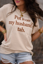 Tan "Put It On My Husband's Tab" T-shirt by P&PD Wholesale, front view showing casual style and printed graphic design.