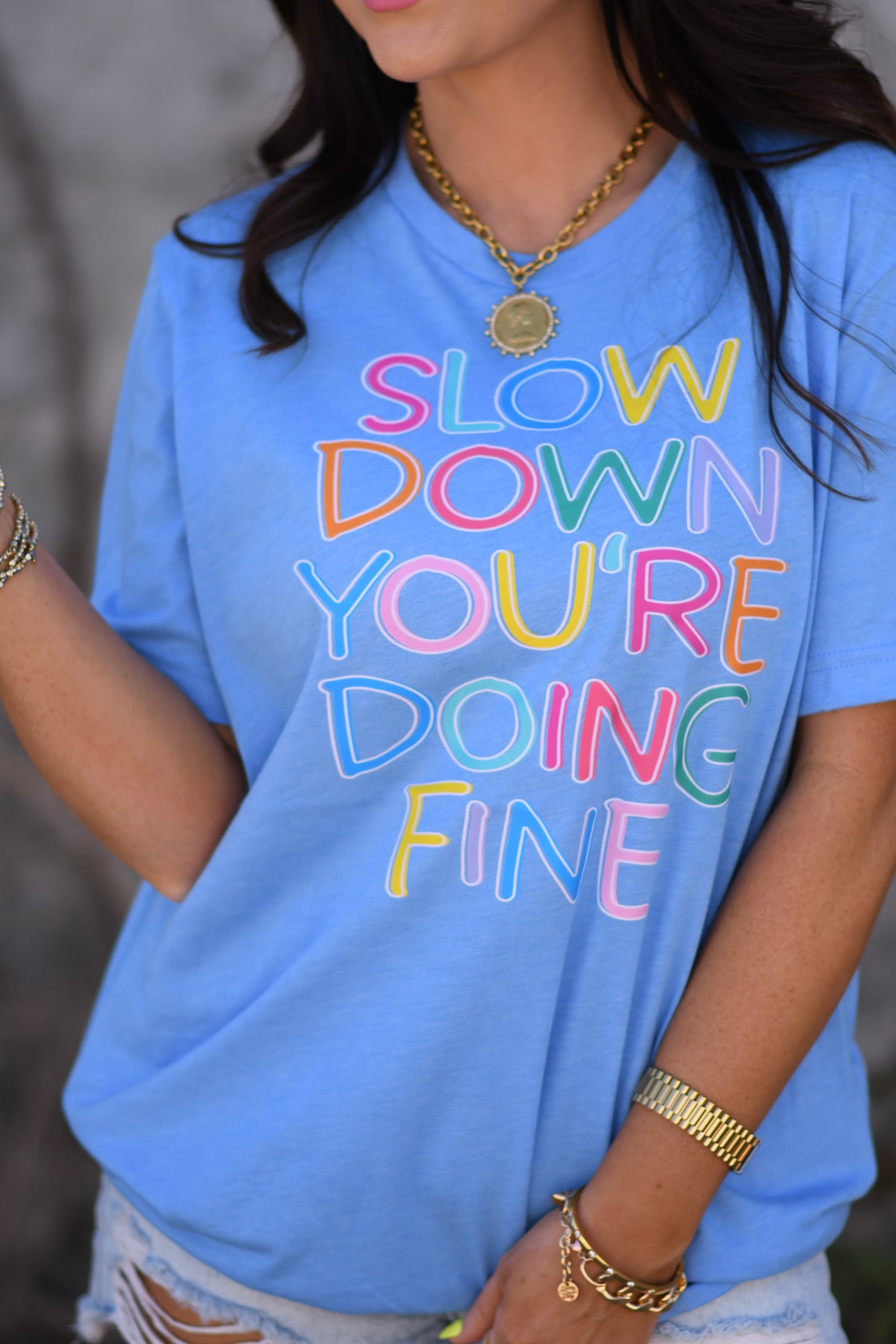 Heather blue P&PD Wholesale "Slow Down You're Doing Fine" graphic tee displayed on a hanger.