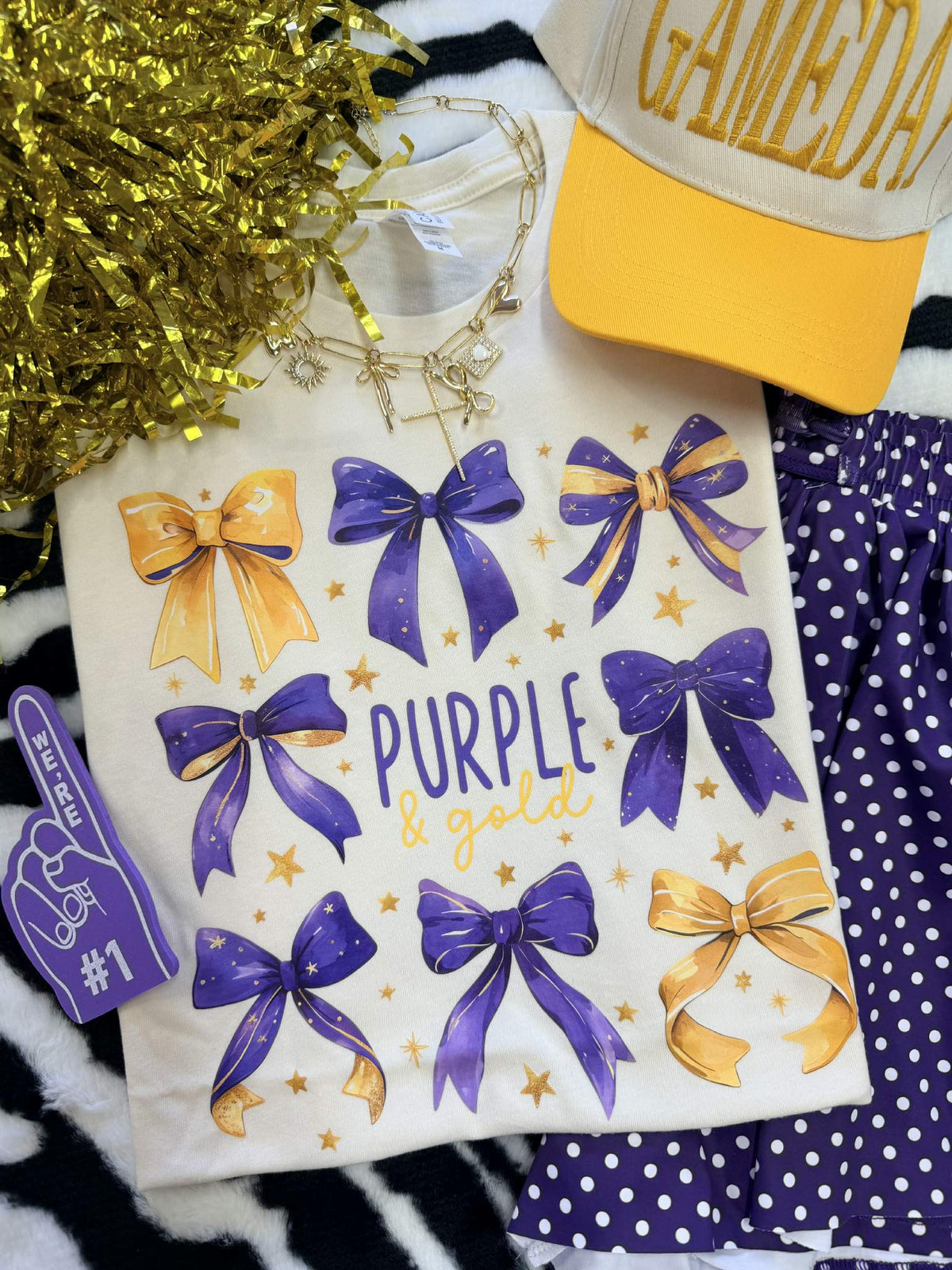 Purple and gold bows T-shirt by P&PD Wholesale featuring a playful bow design on natural-colored fabric.