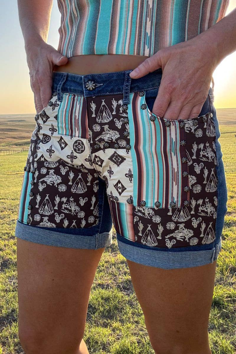 Sterling Kreek Patched Up Western Long Shorts featuring colorful patches and distressed denim design.