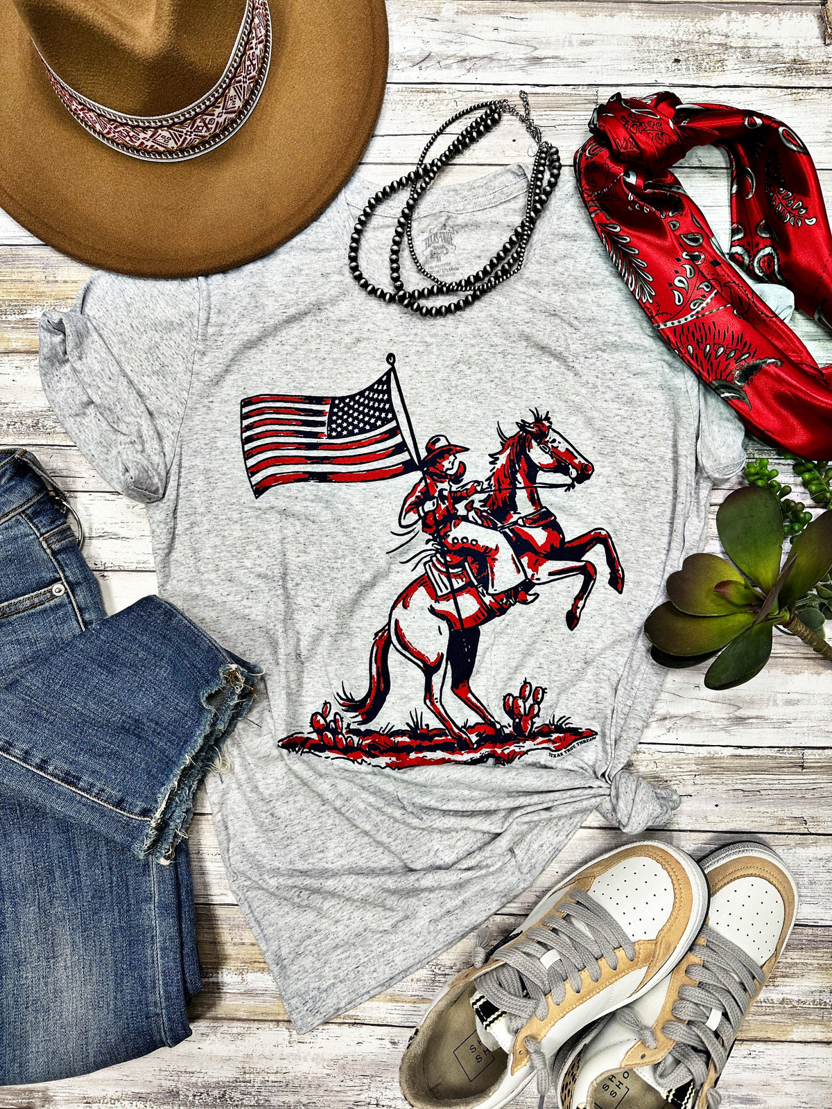 White Patriotic Cowboy Tee by Texas True Threads featuring a patriotic cowboy graphic on the front.